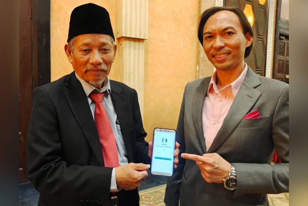 Shaikh Harun (kiri) dan Ahmad Azrin menunjukkan sistem e-Amil yang bakal digunakan secara rasmi bermula 1 Ramadan nanti bagi urusan bayaran zakat fitrah dan harta.