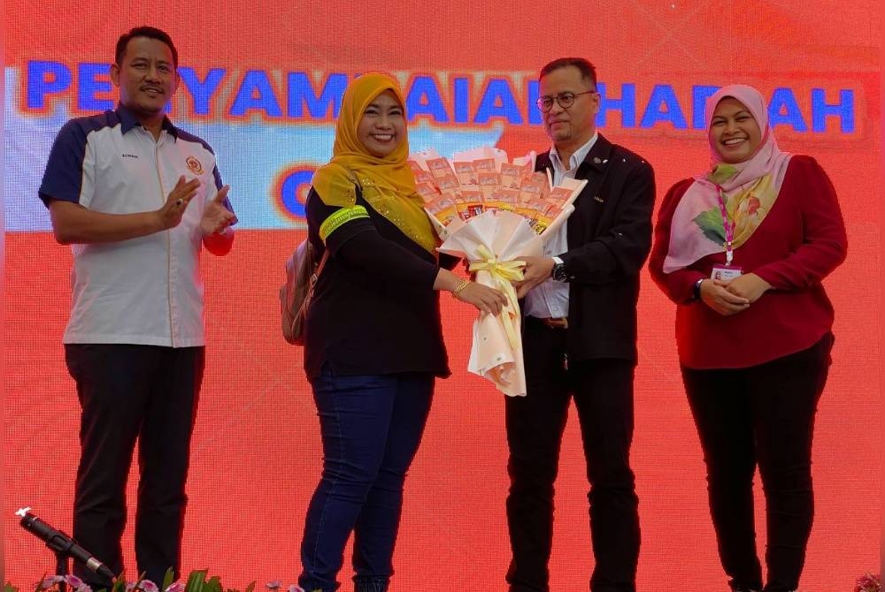 Azman (dua, kanan) menyampaikan hadiah kepada pemenang semasa merasmikan Hari Pengguna Kebangsaan Peringkat Negeri Kelantan di Kota Bharu.