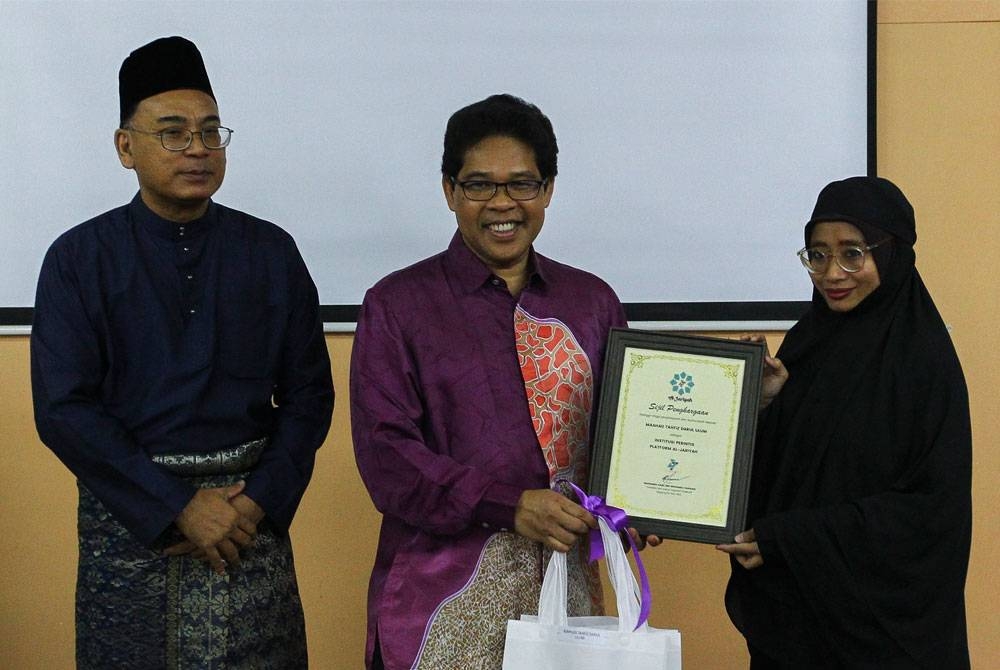 Mohamad Rafie (tengah) menyampaikan cenderahati kepada wakil institusi yang mendaftar Al-Jariyah.