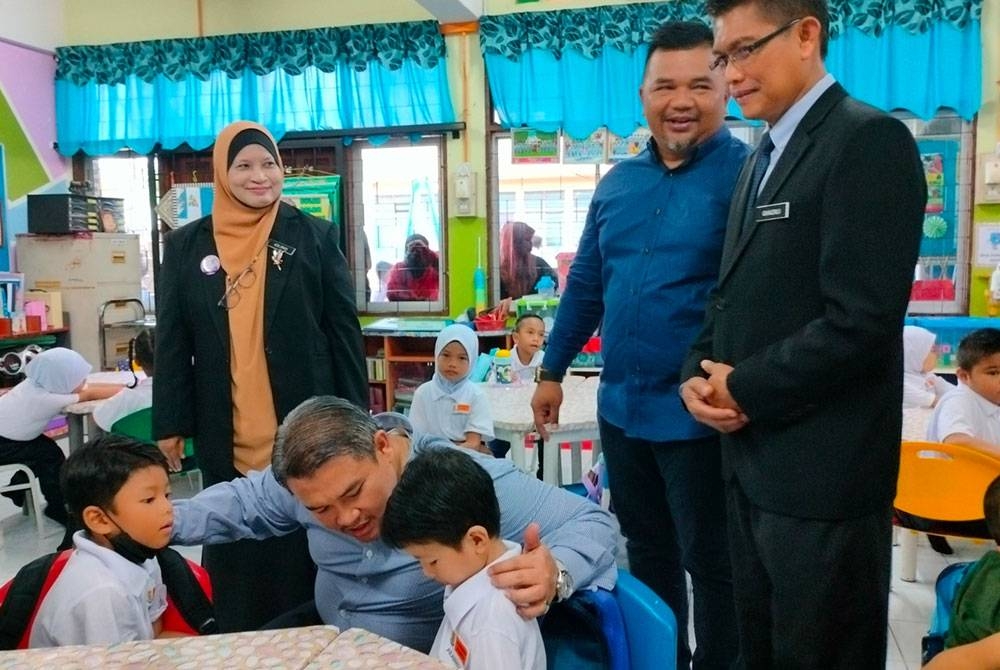 Rais (dua dari kiri) beramah mesra dengan dua murid prasekolah SK Kerubong di Melaka, pada Isnin.