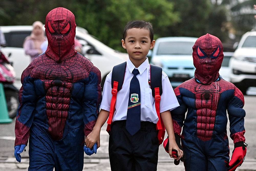 Gelagat seorang murid Tahun Satu Mohd Hanif Adam Shah, 7, (tengah) ditemani kanak-kanak berpakaian kostum Spider-Man pada hari pertama pembukaan sekolah ketika tinjauan di Sekolah Kebangsaan Padang Mengkuang pada Ahad. - Foto Bernama