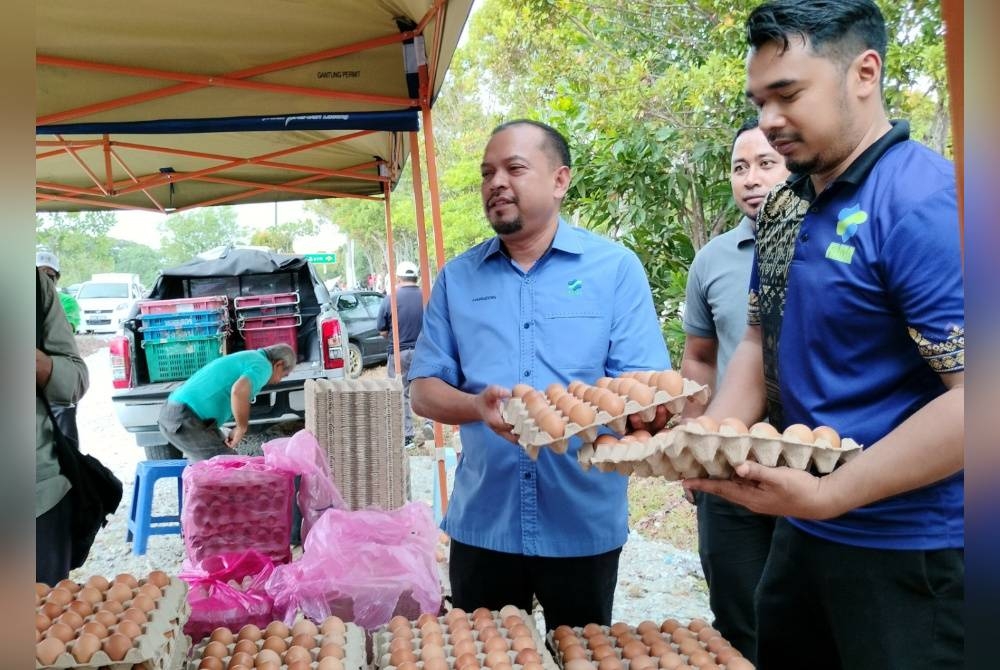 Hairudin (kiri) menunjukkan bekalan telur gred C yang dijual kepada orang ramai pada program itu.