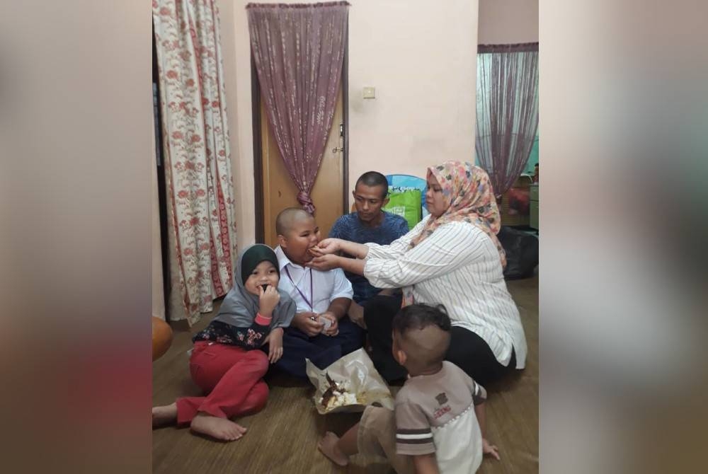 Siti Nuratikah menyuapkan makanan kepada anaknya sambil diperhatikan Zulkifli Ainul di kediaman mereka di PPR Taman Setia Indah, Johor Bahru.