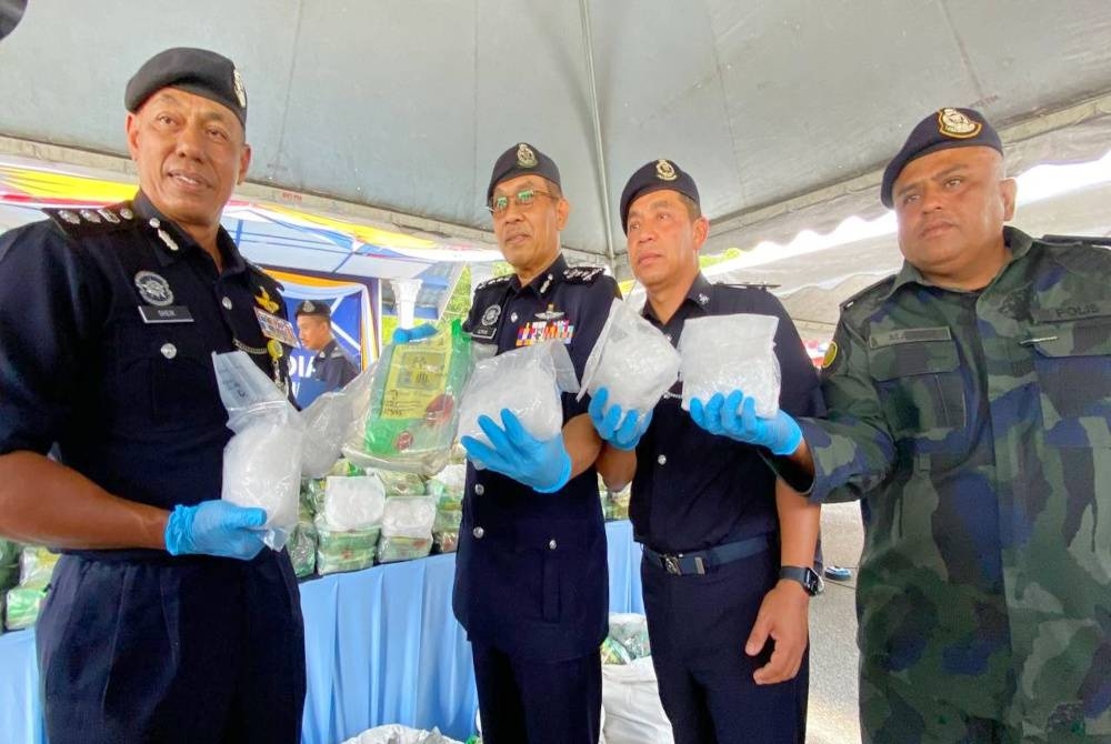 Azman (tiga, kanan) menunjukkan sebahagian daripada dadah yang dirampas semasa sidang akhbar di IPD Tanah Merah pada Rabu.