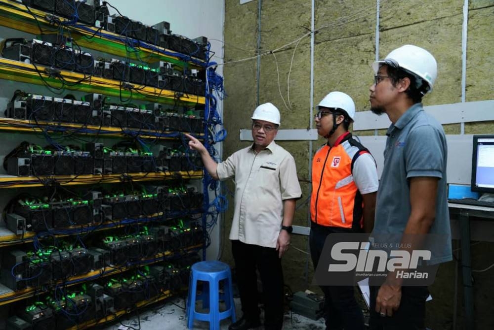 Ir Md Zakuan (kiri) menunjukkan antara mesin perlombangan bitcoin di premis yang diserbu di Setia Alam pada Rabu. - Foto Sinar Harian/ MOHD HALIM ABDUL WAHID