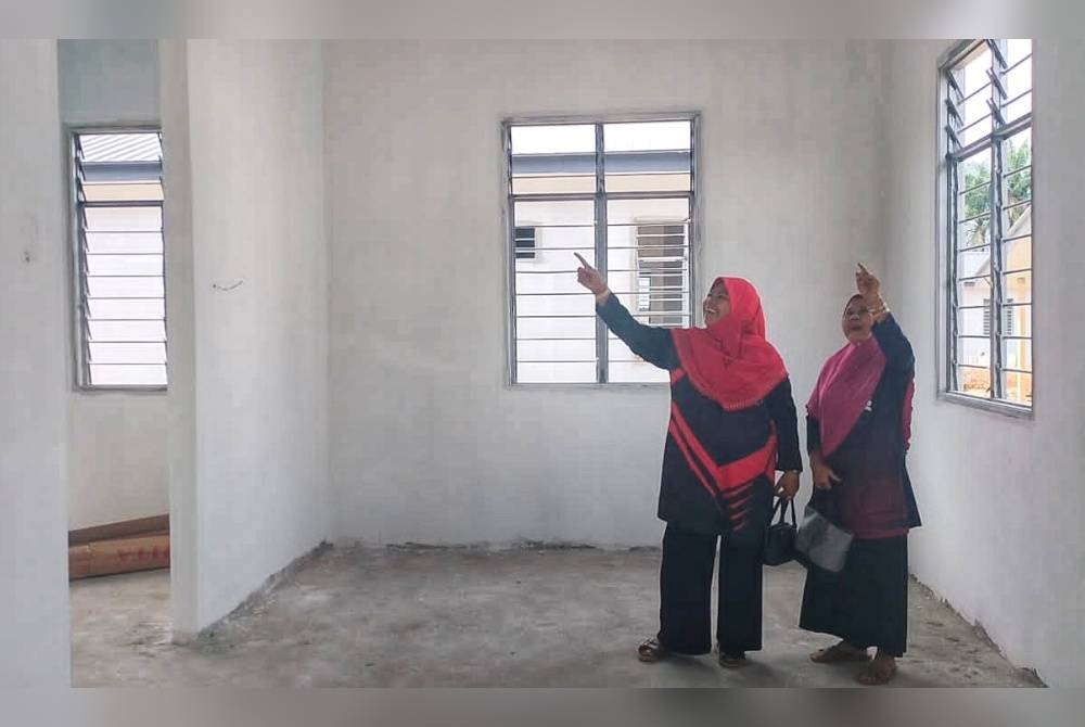 Maznah (kanan) meninjau rumah baharu mereka yang hampir siap di Desa KEDA Kampung Sadek, Baling.