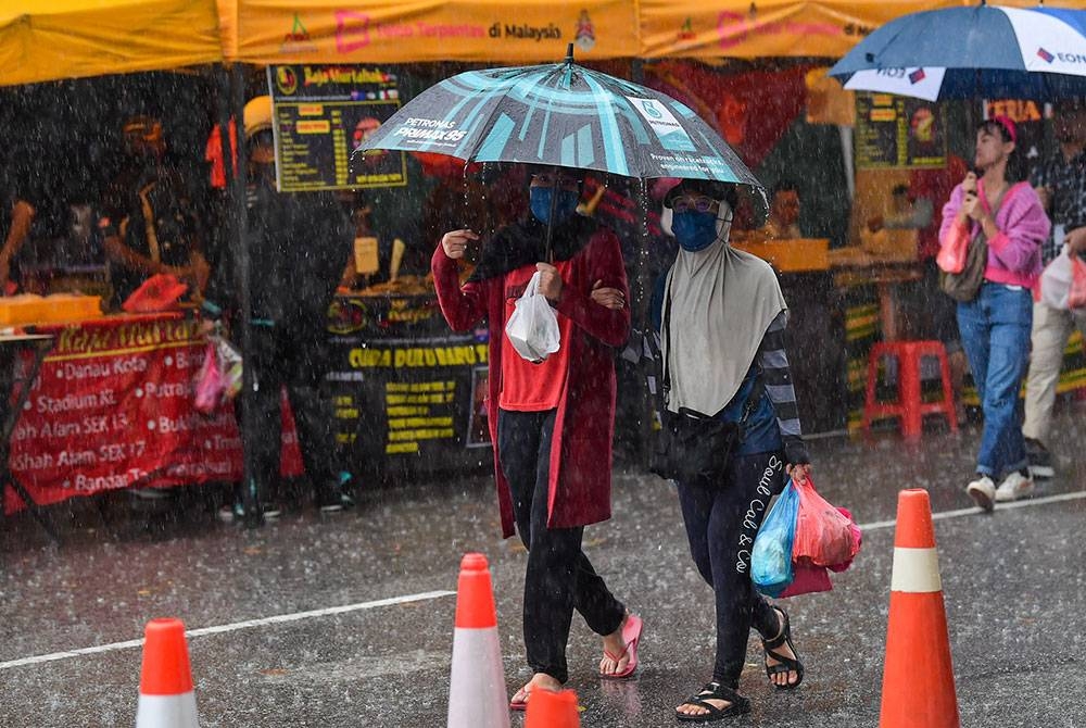 Suasana hujan lebat ketika orang ramai keluar membeli juadah berbuka puasa pada hari pertama Ramadan di bazar Ramadan TTDI, pada Khamis. - Foto Bernama