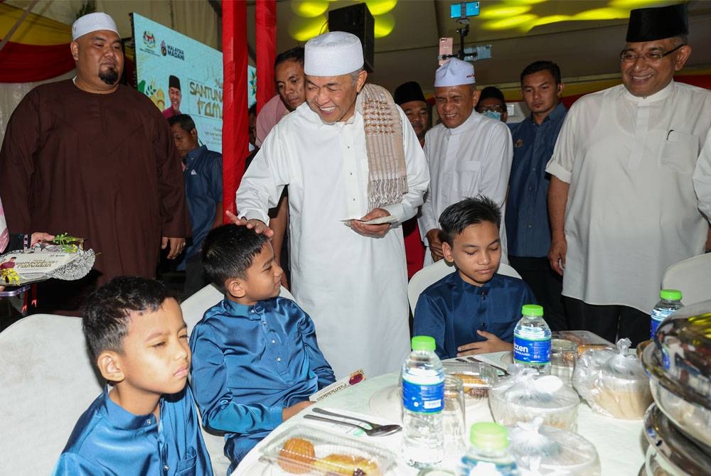 Ahmad Zahid menyampaikan sumbangan duit raya kepada anak-anak yatim sempena Majlis Santunan Kasih Ramadan 1444H Kementerian Kemajuan Desa dan Wilayah Negeri Selangor di Masjid Batu 8, Gombak Utara pada Jumaat. - Foto Bernama