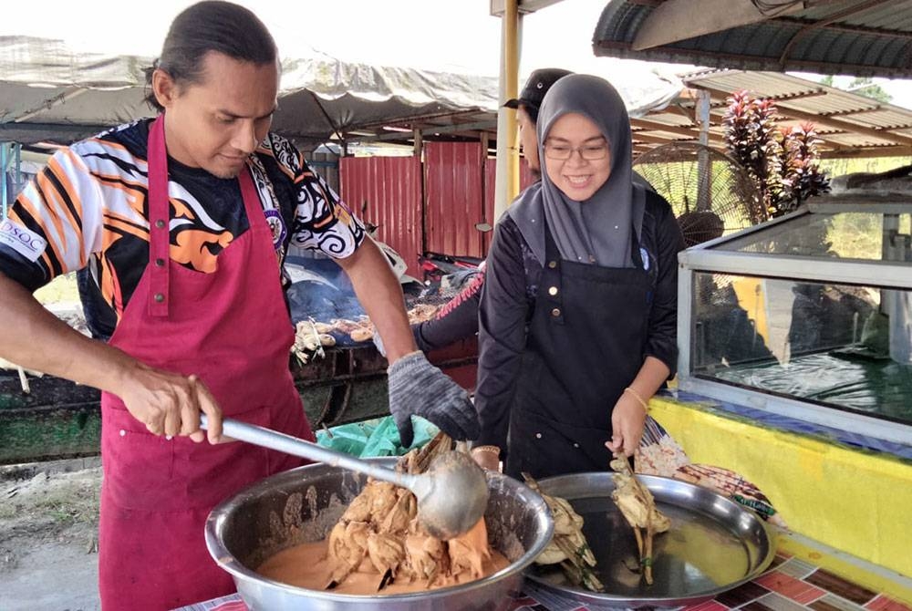 Mohd Zaidi (kiri) menyiram kuah percik sebelum membakar ayam sambil diperhatikan Madihah.