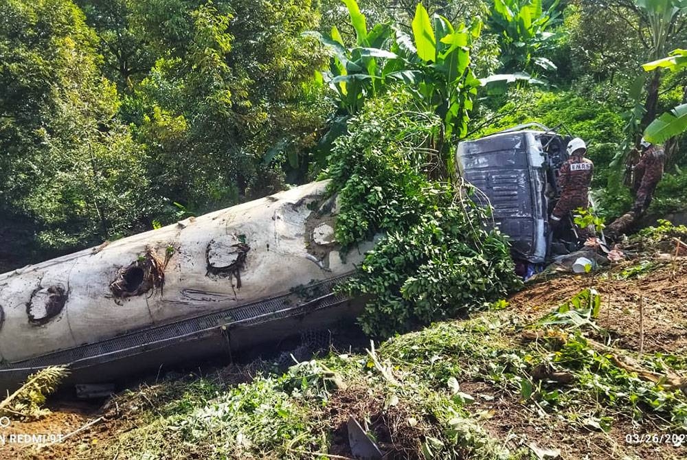 Anggota bomba membuat pemeriksaan pada lori tersebut yang terjatuh ke dalam gaung di KM42.3 LPT hala Timur pada Ahad. - Foto JBPM