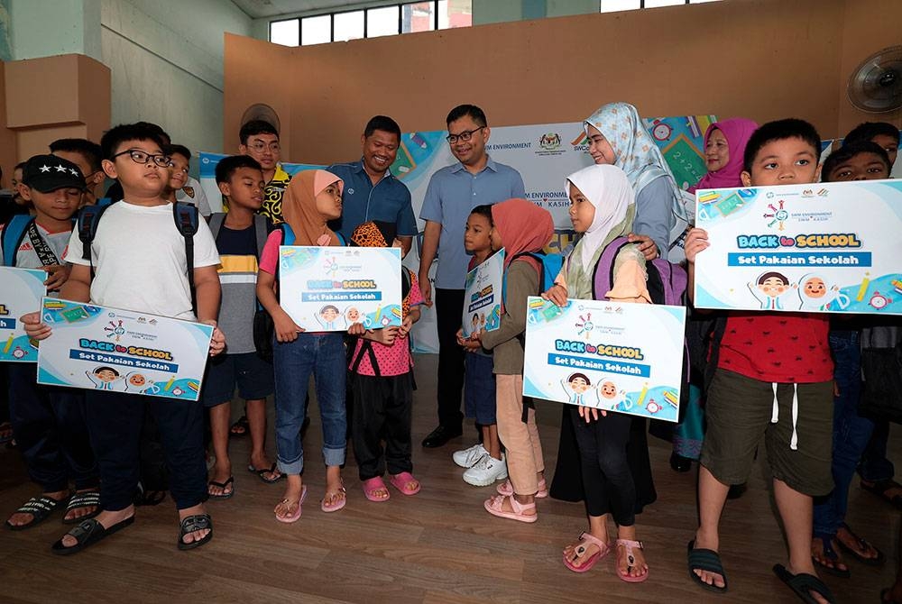 Akmal Nasrullah dan Mohd Norlisam beramah mesra dengan kanak-kanak yang menerima barang kelengkapan persekolahan pada Program CSR SWM Kasih Back To School di Dewan Flat Larkin, Johor Bahru, pada Ahad. - Foto Bernama