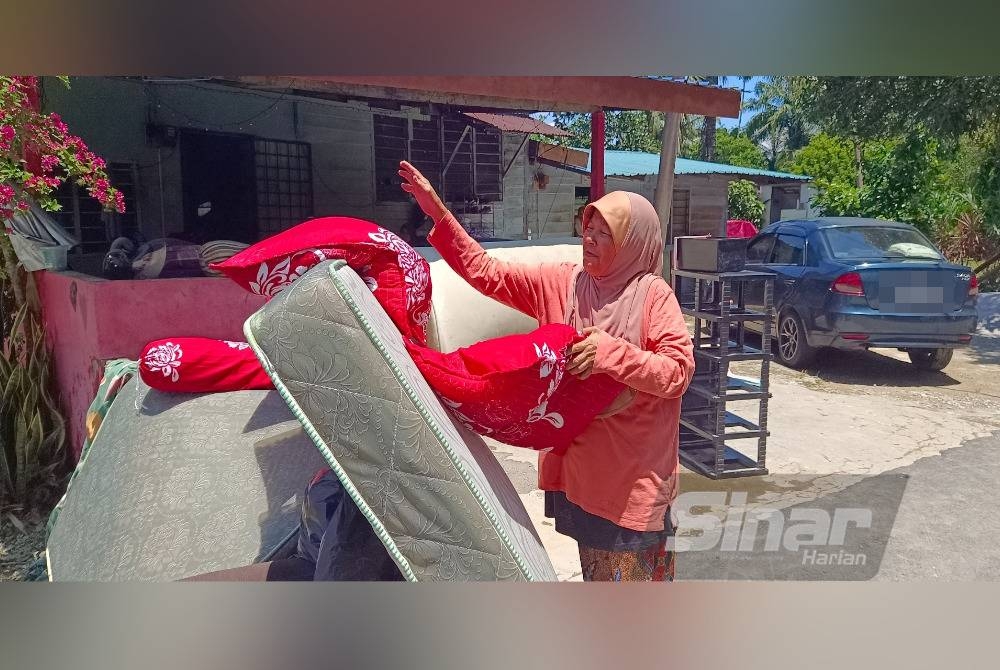 Zaitun mengeringkan bantal dan tilam yang basah akibat banjir di Kampung Sungai Relong, Kamunting pada Ahad.