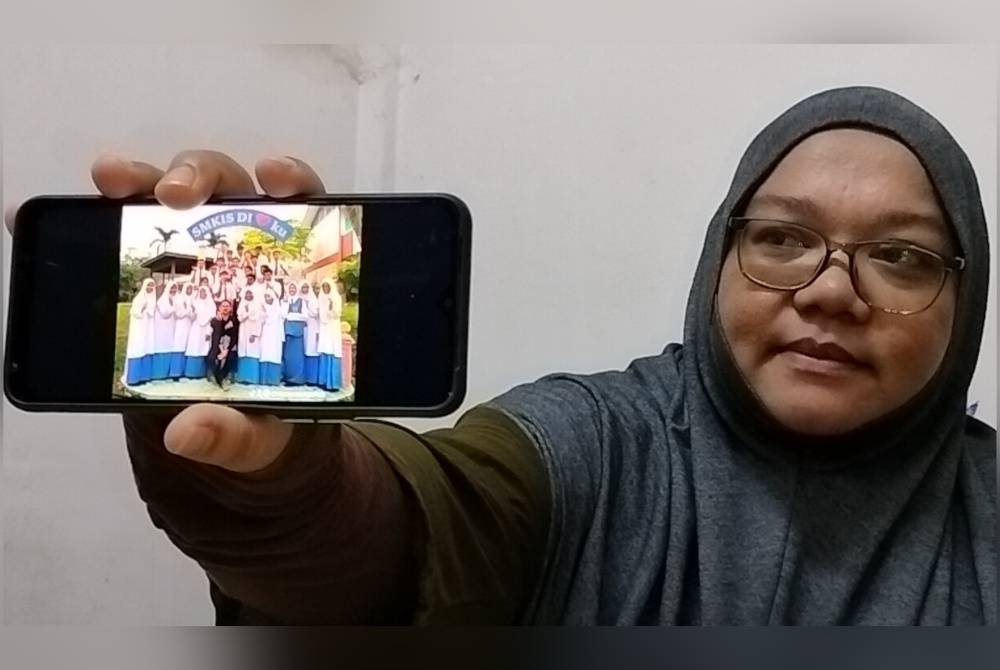 Noor Fatimahtul Zaharah menunjukkan gambar anaknya yang beruniform pengawas bersama rakan sekolah.