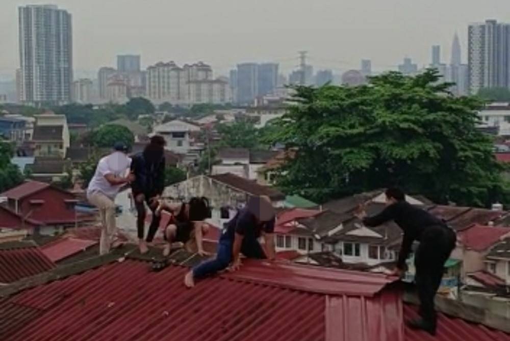 Pihak berkuasa (kanan) cuba menghalang tindakan beberapa individu disyaki pengedar dadah meloloskan diri menerusi bumbung sebuah flat di Jinjang, Kuala Lumpur dalam serbuan pada Isnin.