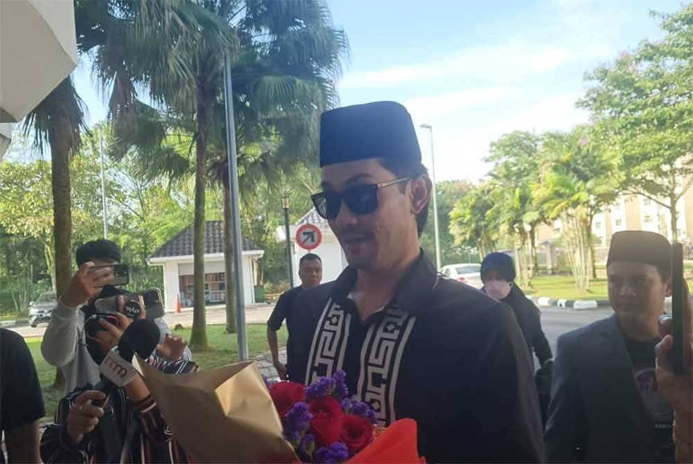 Farid dilihat memegang sejambak bunga mawa ketika tiba di pekarangan Mahkamah Syariah Subang Bestari pada Selasa.