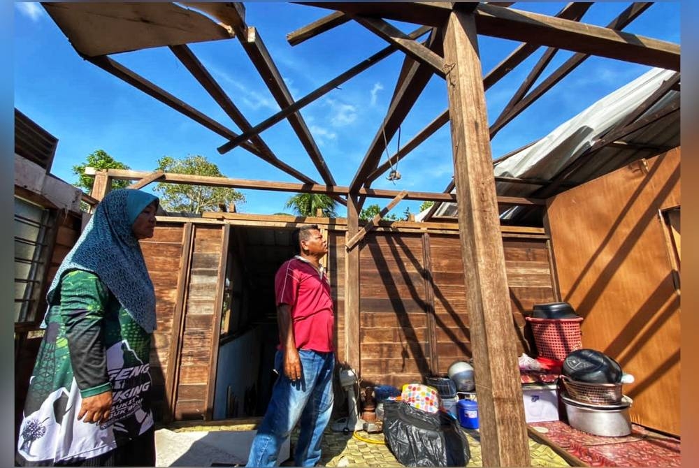 
Abdul Rahim dan Badariah menunjukkan bumbung rumah mereka yang diterbangkan ribut dalam kejadian petang Isnin.