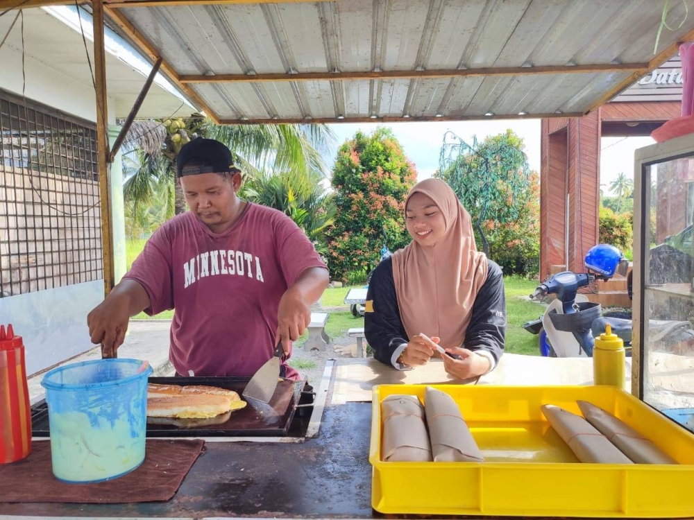 Abdul Razif (kiri) ketika menyiapkan roti john di bazar Ramadan Mini depan pintu gerbang Kampung Lonek,Jempol.