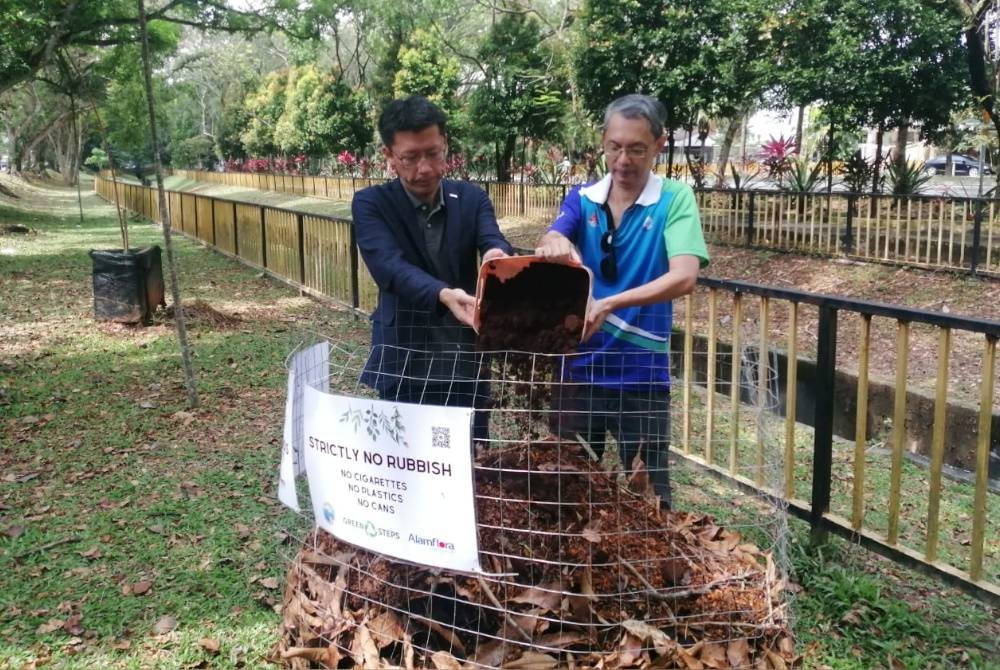 Keisuke Nishida (kiri) dan Azlan menunjukkan sisa makanan yang dikompos menjadi baja untuk kegunaan kebun tanaman di TTDI.