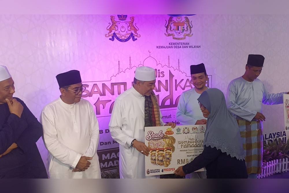 Ahmad Zahid (tengah) menyerahkan peruntukan kepada usahawan desa di Masjid Jamek Kampung Sungai Gersik Sungai Balang, Muar pada Khamis.