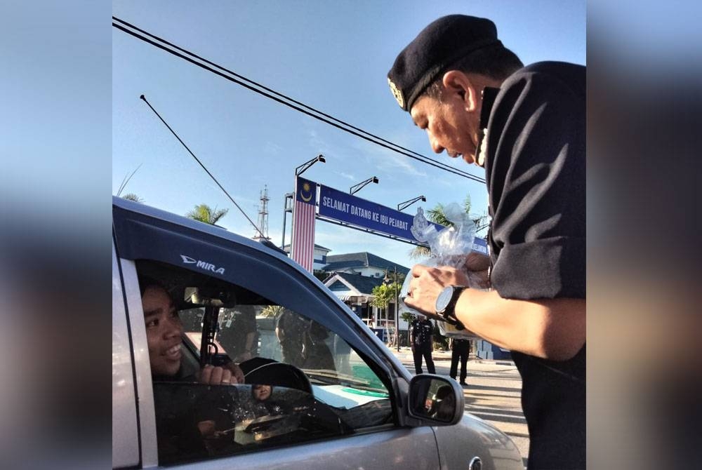 Muhamad Zaki bertanya khabar pengguna jalan raya ketika program mengagihkan bubur lambuk pada Khamis.