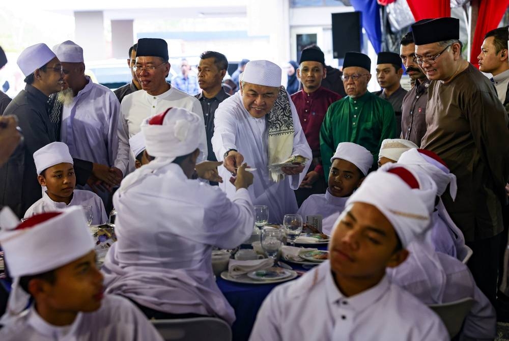 Ahmad Zahid menyampaikan duit raya kepada anak-anak yatim yang hadir pada Majlis Santunan Kasih Ramadan Negeri Perak 2023 di Sekolah Izzudin Shah pada Jumaat.