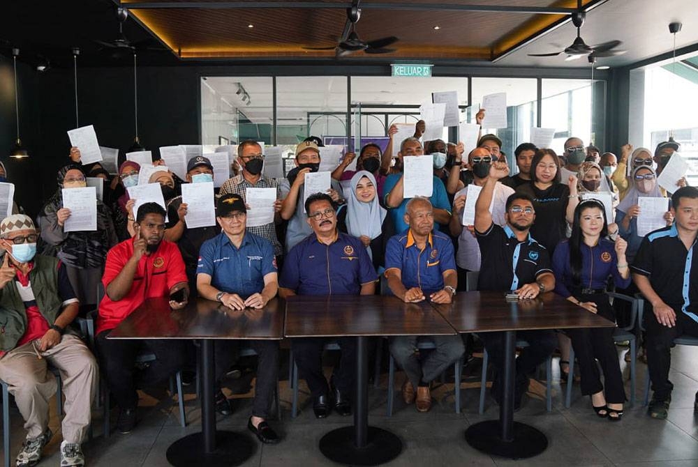 Hishamuddin (duduk, tiga dari kanan) bersama mangsa penipuan pelaburan saham menunjukkan laporan polis selepas sidang media yang diadakan di Sungai Besi.