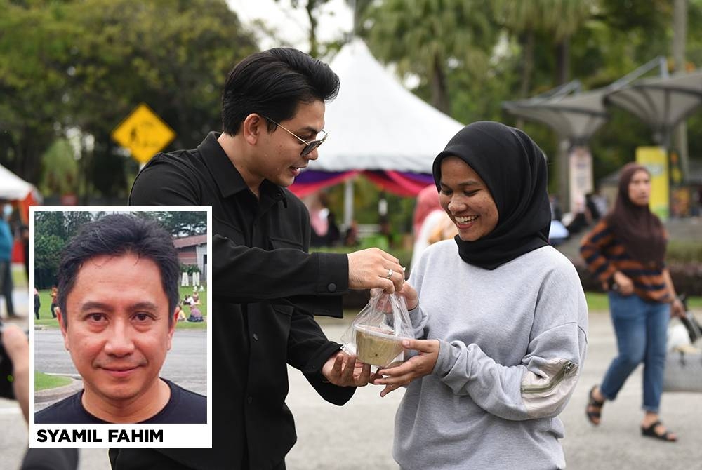 Artis Izzue Islam memberi bubur lambuk kepada pengunjung di Dataran Kemerdekaan.