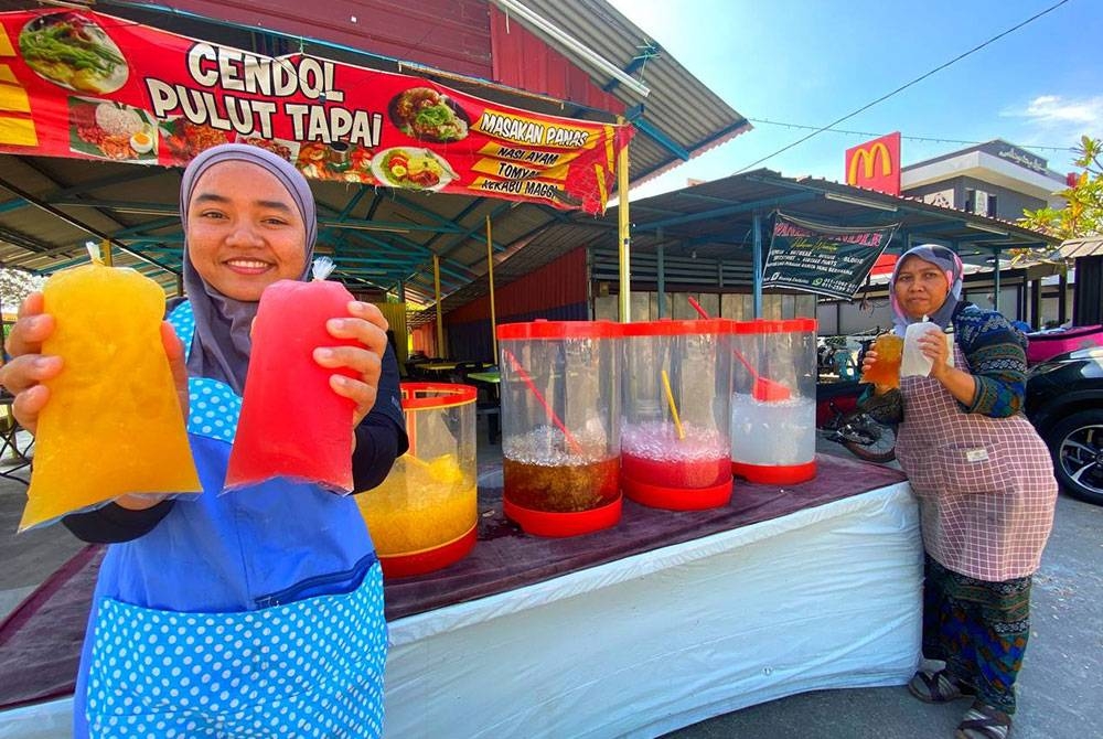 Hamizon (kanan) dan anak perempuannya menunjukkan air buah yang dijual dengan harga RM1 sebungkus di gerai mereka di Kok Lanas, Kota Bharu.