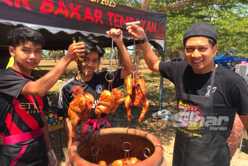 Nur Izwan (kanan) dan pekerja-pekerjanya menunjukkan ayam panggang tempayan.