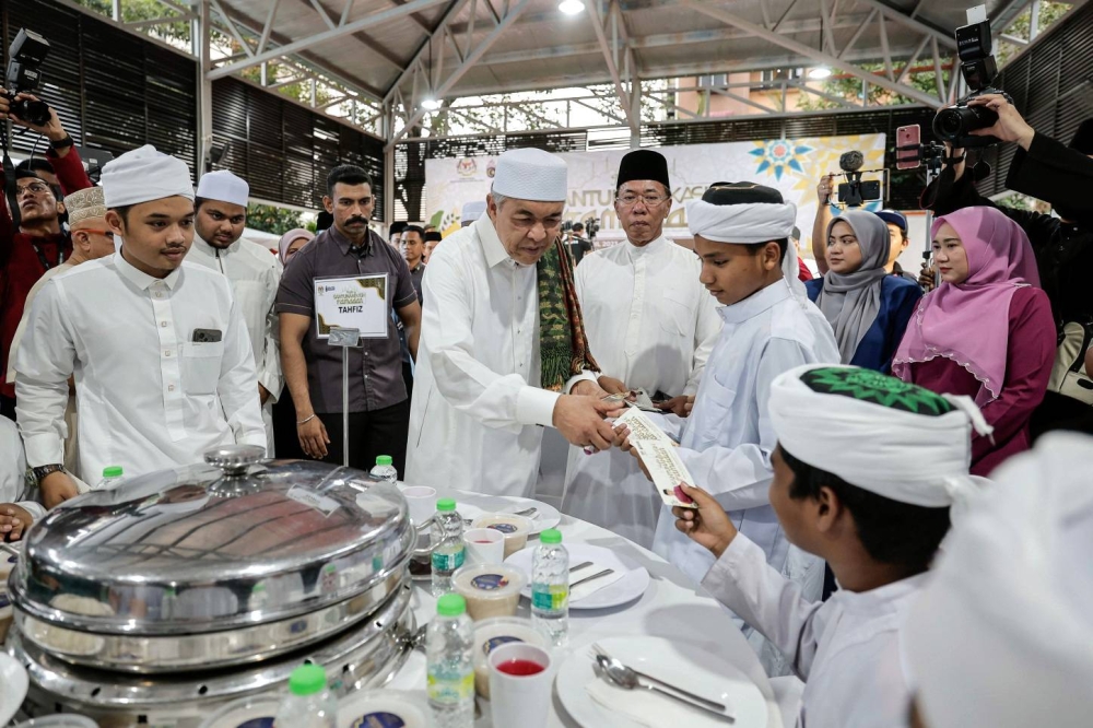 Ahmad Zahid menyampaikan sumbangan kepada pelajar-pelajar Tahfiz pada Majlis Santunan Kasih Ramadan di Dewan Projek Perumahan Rakyat (PPR) Seri Semarak hari ini. - Foto Bernama