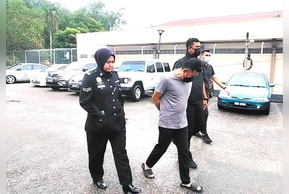 Hoe Kian Lim (tengah) ketika diiring polis di Mahkamah Sesyen Kuala Pilah pada Isnin.