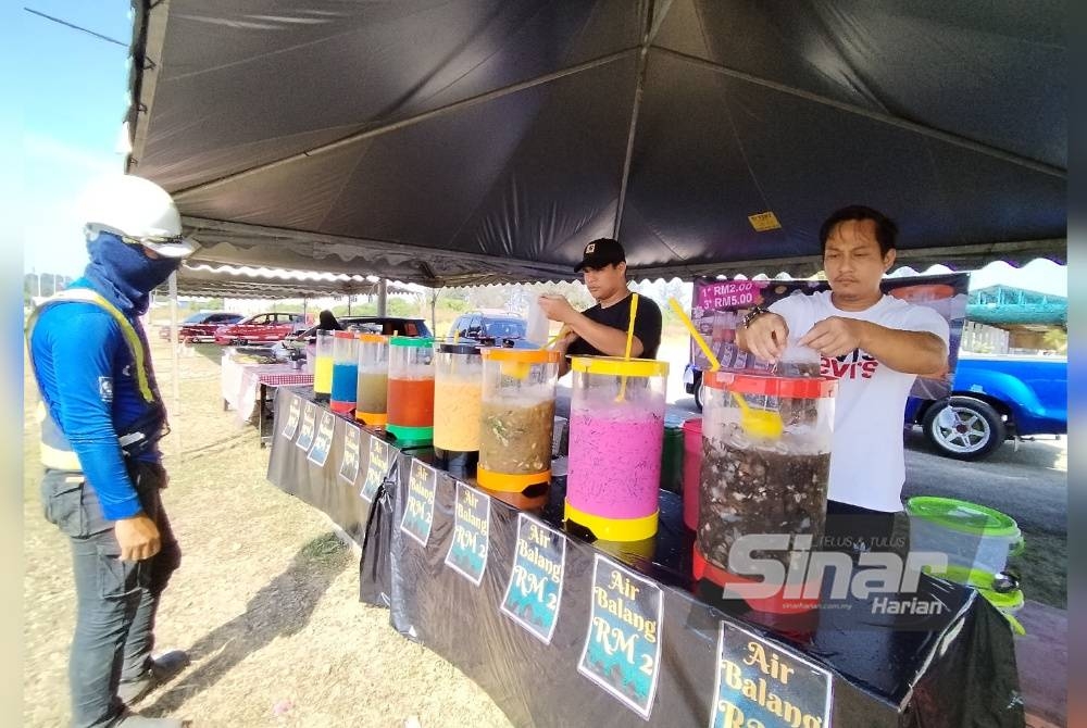 Mohammad Ariffuddin membungkus air balang yang dibeli pelanggan di gerainya yang terletak di hadapan kolam memancing Kail Life Seberang Balok.