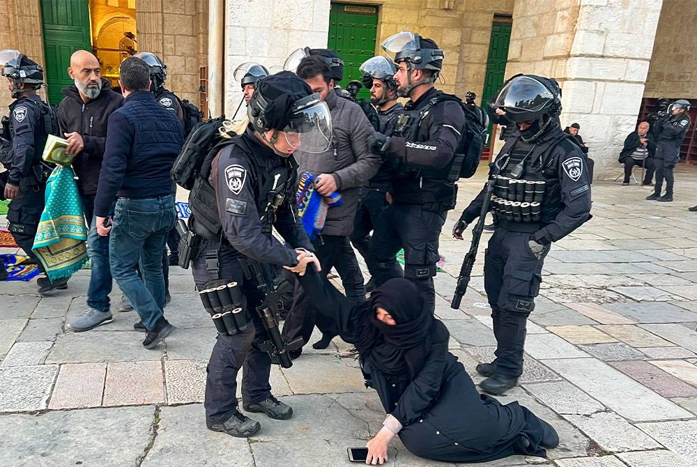 Anggota polis Israel cuba mengheret seorang wanita Palestin yang duduk di Haram Sharif pada awal pagi Rabu. - Foto AFP