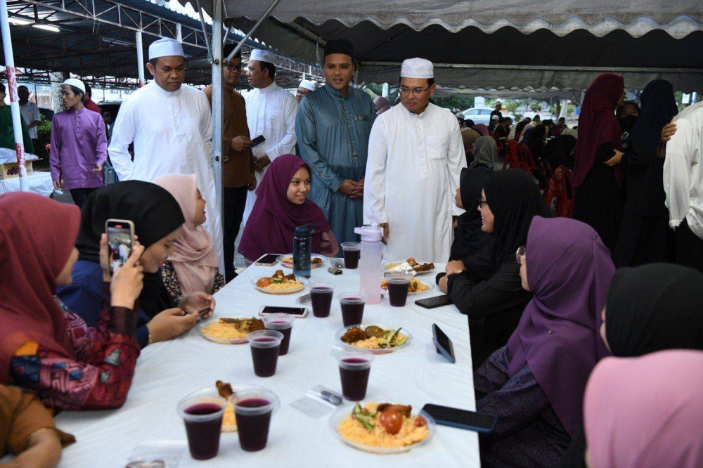 Fadzli (berdiri, kanan) bertanya khabar pelajar yang hadir berbuka puasa secara percuma di Masjid UniSZA. - Foto UniSZA