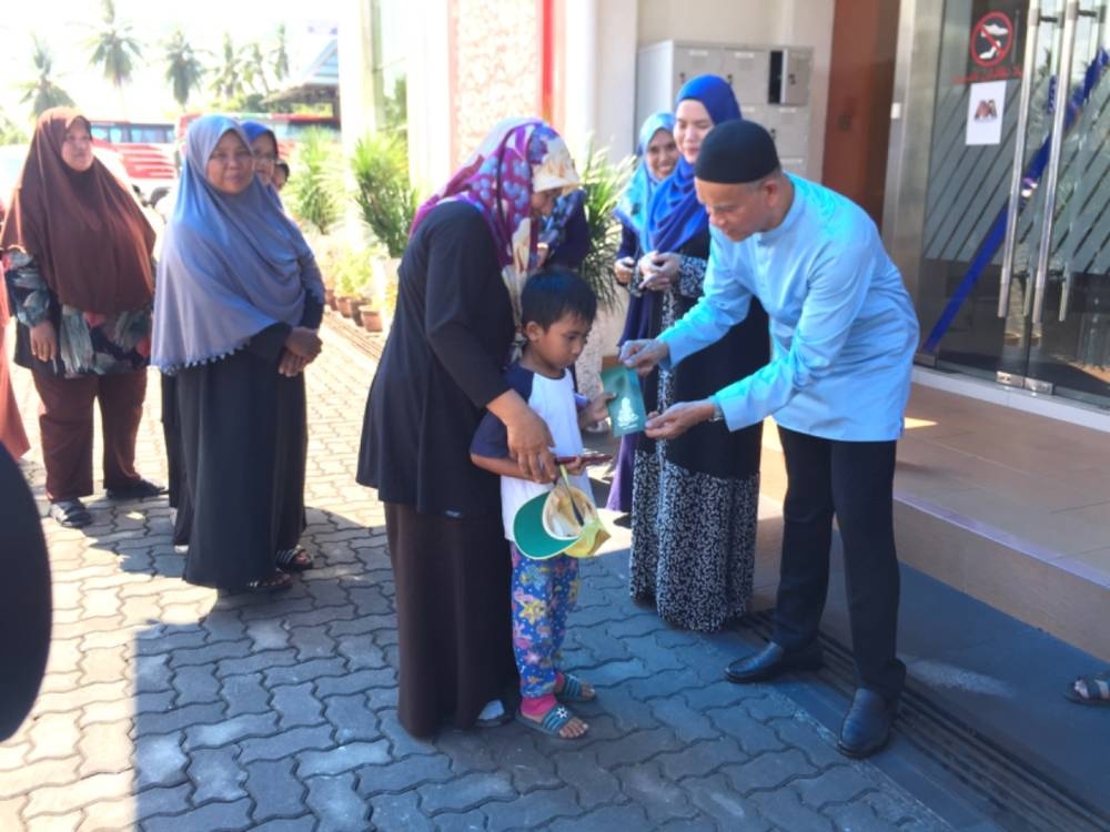 Che Ibrahim (kanan) menyampaikan zakat kepada suri rumah, Tuan Hasnah Tuan Ismail (tengah).