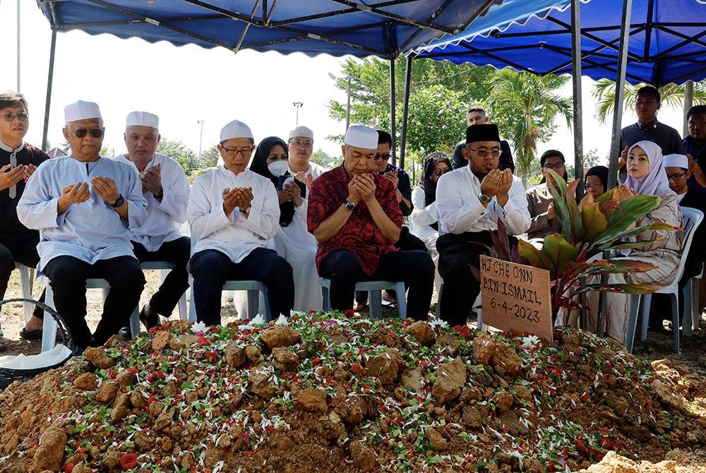 Ahmad Zahid (depan, tiga dari kiri) bersama keluarga Allahyarham mengaminkan doa di pusara Onn Ismail di Tanah Perkuburan Islam Kampung Raja Uda pada Khamis. - Foto Bernama