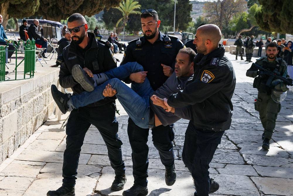 Tentera Israel menahan seorang penduduk Palestin semasa mereka melakukan serbuan di perkarangan masjid Al-Aqsa. - Foto AFP