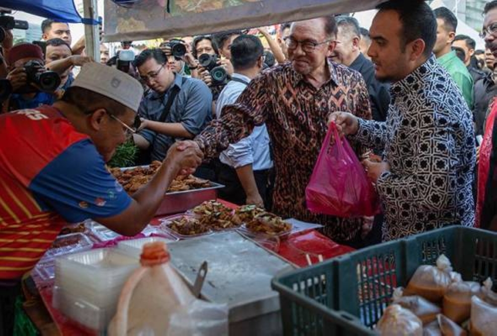 Anwar beramah mesra dengan peniaga selepas melancarkan Program Jualan Agro Rahmah bazar Ramadan Presint 3, Putrajaya, petang ini. - Foto Awani