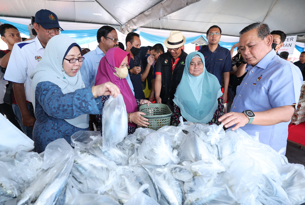 Fuziah (kiri) bersama Aminuddin (kanan) membantu memilih ikan kembung untuk pembeli ketika melancarkan Jualan Rahmah peringkat negeri di sebuah pasar raya pada Jumaat. - Foto Bernama