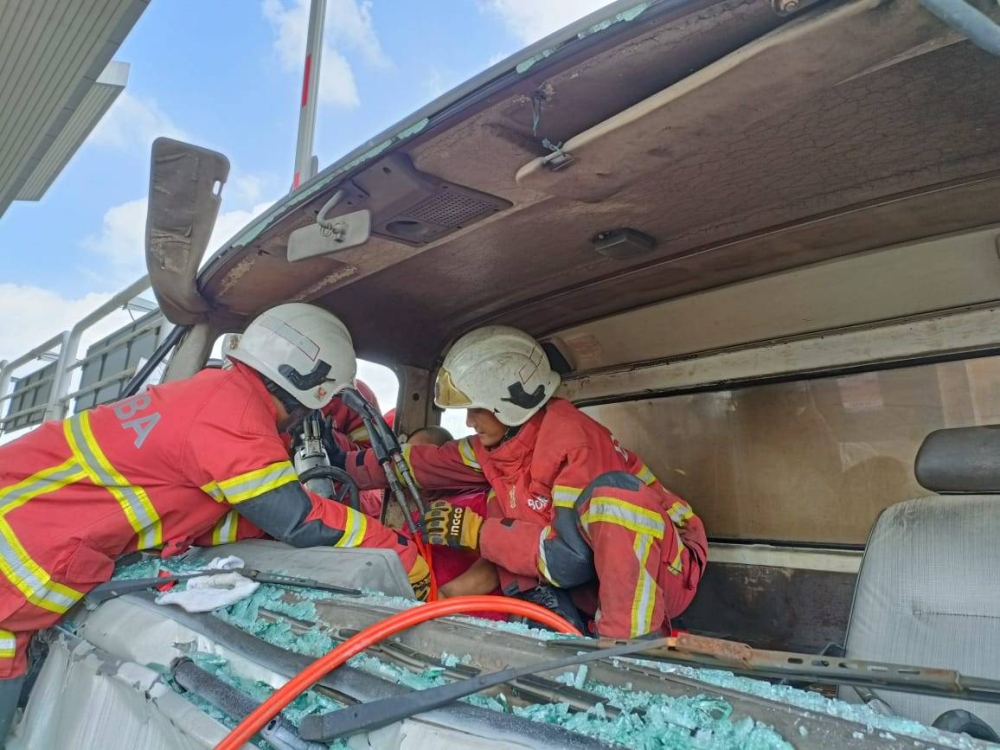 Anggota bomba berusaha menyelamatkan mangsa yang tersepit selepas bertembung dengan sebuah lagi lori di Plaza Tol LKSA Alam Impian, dekat sini pada Jumaat.