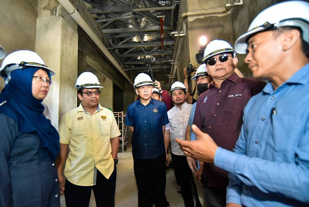 Zaliha (kiri) mendengar taklimat berhubung perkembangan pembinaan Hospital Papar dalam lawatan kerjanya di Papar.