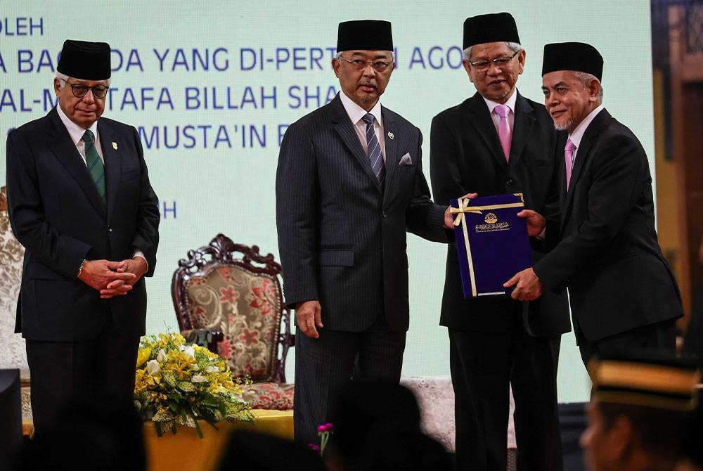 Al Sultan Abdullah (dua dari kiri) berkenan menyampaikan watikah hakim syarie kepada Ketua Hakim Syarie Pulau Pinang Datuk Muhamad Abdul Karim Wahab (kanan) pada Majlis Pengurniaan Watikah Pelantikan Ahli Majlis Agama Islam Dan Hakim Syarie Negeri Pulau Pinang hari ini. - Foto Bernama