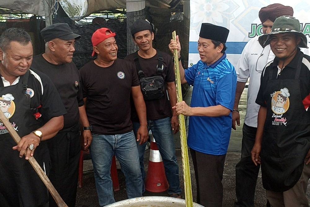 Ahmad (dua dari kanan) mengacau bubur lambuk bersama rukun tetangga di Ayer Baloi pada Sabtu.