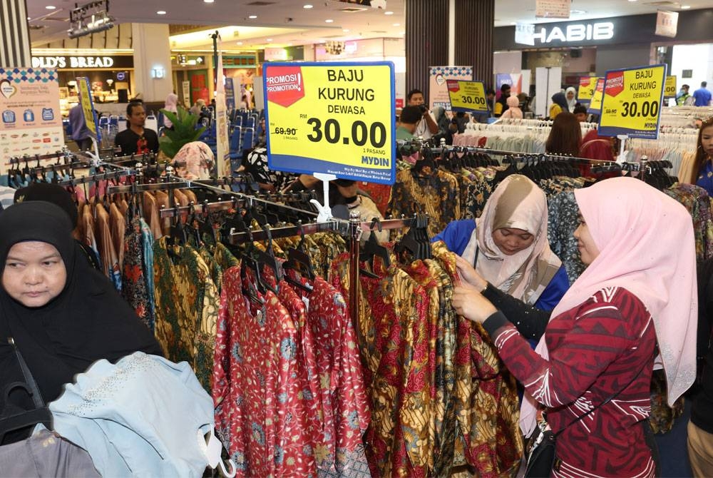 Orang ramai berpusu-pusu membeli baju raya dengan harga murah sebanyak RM30 sepasang untuk dewasa dan kanak-kanak ketika pelancaran Kempen "Klasiknya Raya” di MYDIN Subang Jaya. - Foto Bernama.