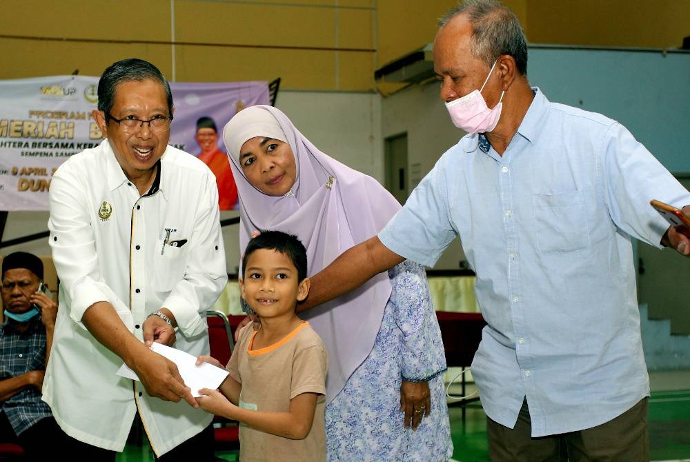 Mohammad Nizar (kiri) menyampaikan sumbangan kepada penerima ketika Program Meriah Beraya Sejahtera Bersama Kerajaan Negeri Perak di Dewan Carsem, Maju Rapat di sini pada Ahad.