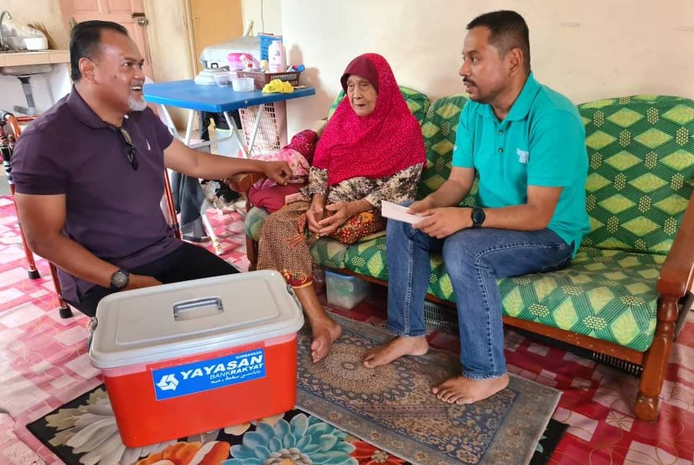 Syaiful Rizal (kanan) dan Rizal (kiri) ketika menyampaikan bakul makanan kepada asnaf di sekitar Padang Besar pada Jumaat.