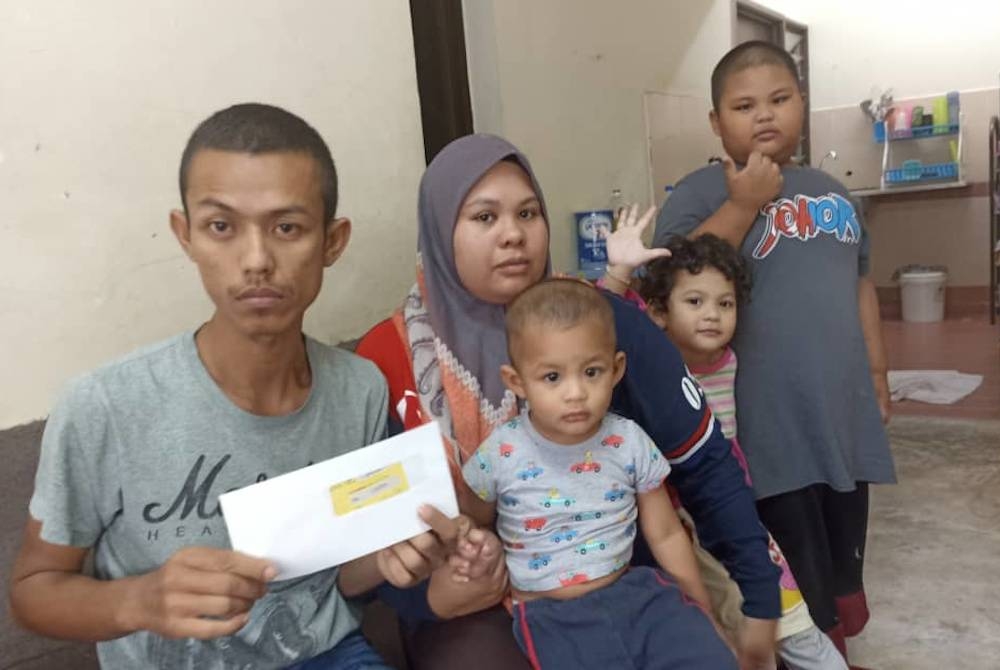 Zulkifli bersama Siti Nuratikah dan tiga anak mereka menerima sumbangan wang tunai daripada Yayasan Nur Karangkraf.