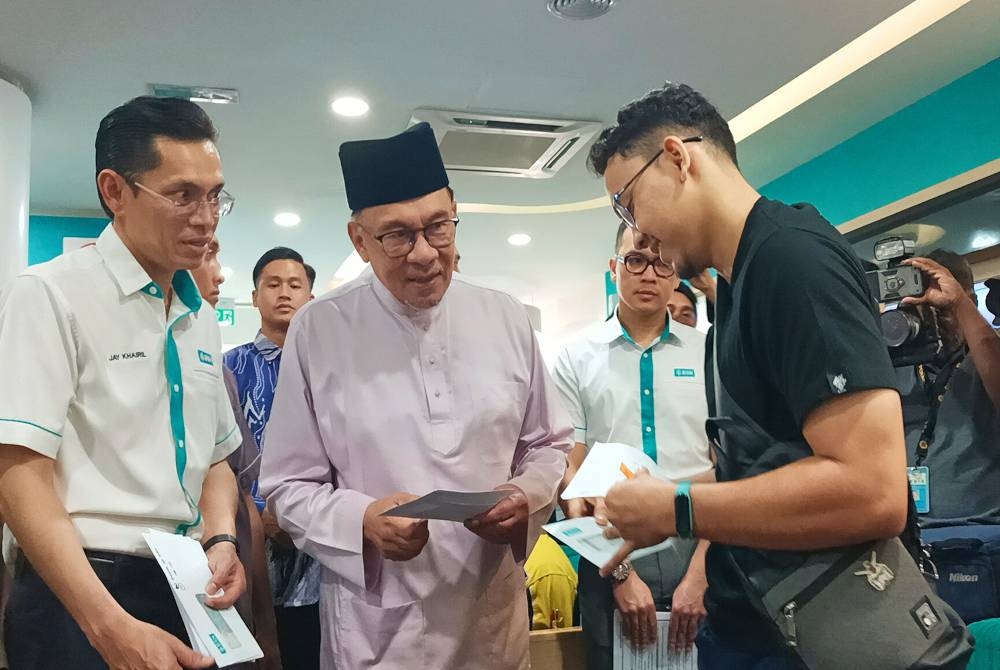 Anwar (tengah) dalam program penyampaian Sumbangan Tunai Rahmah Fasa 2 (STR2) di Bank Simpanan Nasional (BSN) Cawangan Bandar Meru Raya, Ipoh pada Isnin.