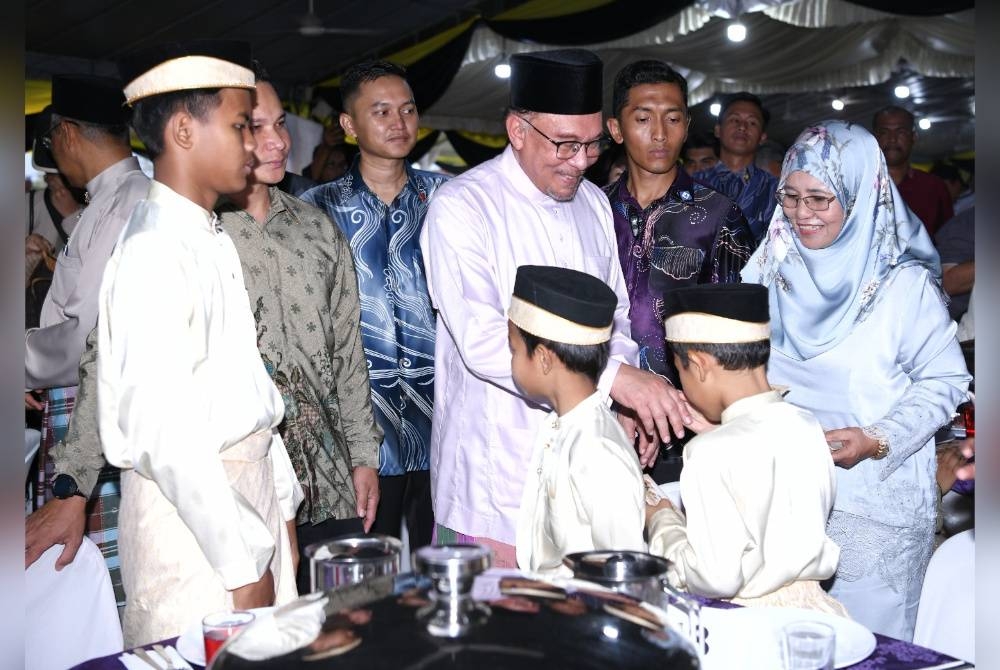 Hamidah (kanan) mengiringi Anwar menyampaikan sumbangan kepada anak-anak yatim terpilih ketika Majlis Berbuka Puasa di Masjid Ittihadiah, Manjoi di sini pada Isnin.