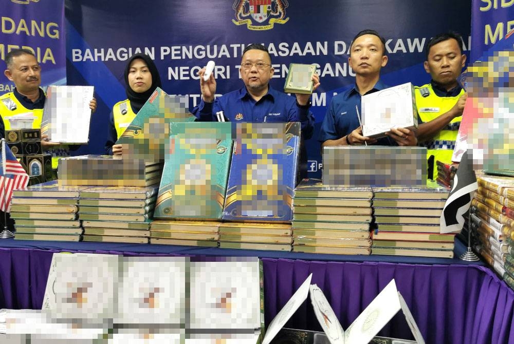 Nik Yusaimi (tengah) menunjukkan antara al-Quran yang dirampas dalam serbuan dijalankan ke atas sebuah premis di Jerteh, Besut dalam sidang akhbar di Pejabat Bahagian Penguatkuasaan dan Kawalan (PK), KDN Terengganu, di Kuala Terengganu pada Selasa.